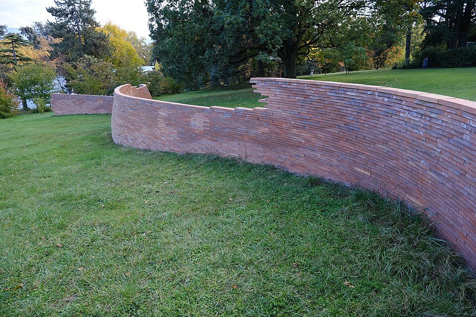 The curved brick wall of the MUR murs installation rising along the slope