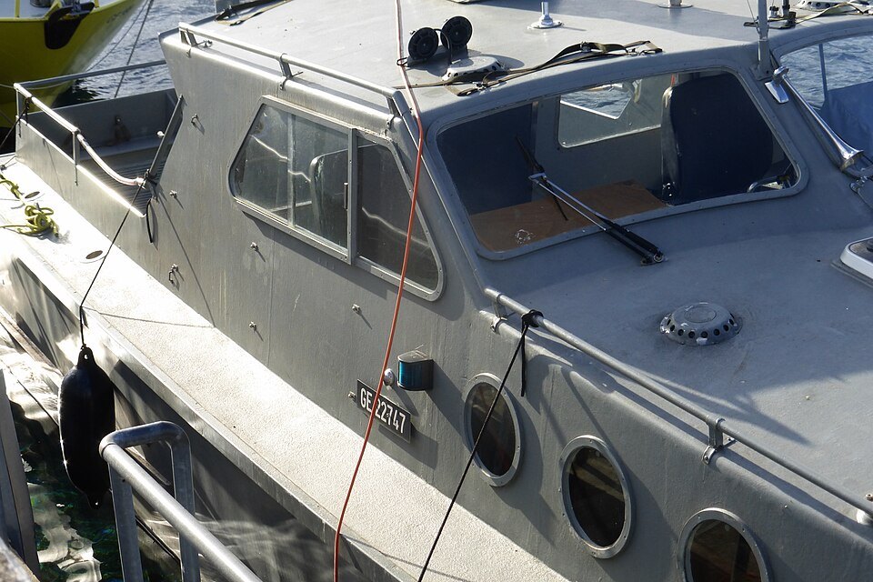 The gray hull and cabin of a lake rescue boat moored at the Pâquis