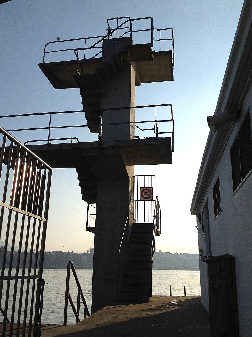 The concrete diving tower at the Bains des Pâquis, dark against the lake