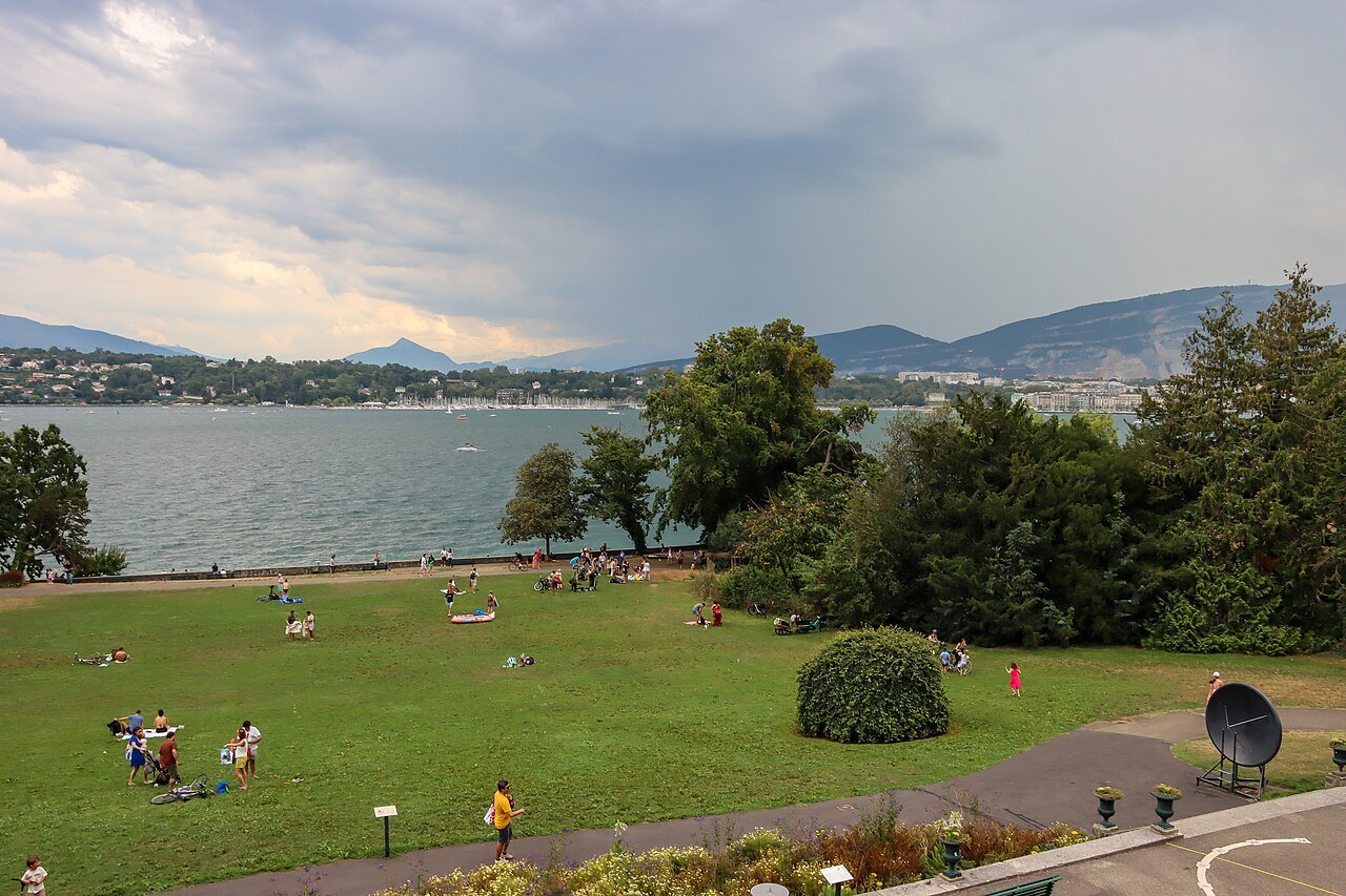 People on the lawns of the lakeside park, the lake and the hills of the far shore beyond
