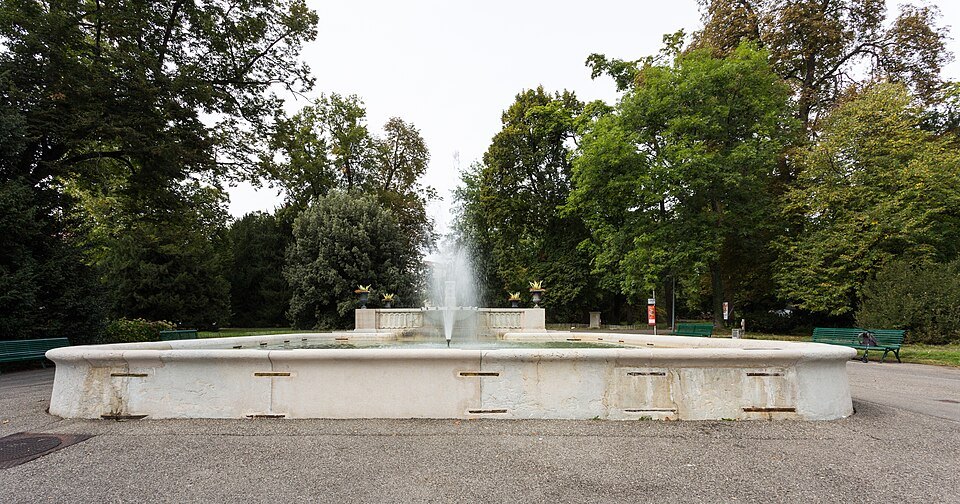 A wide fountain basin among the trees of the lakeside parks
