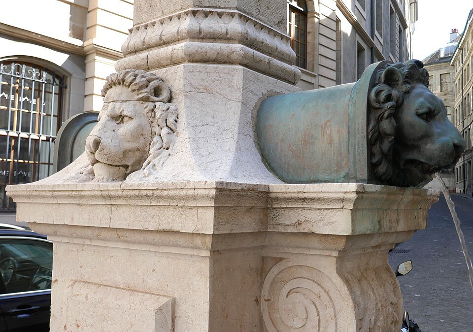 Bronze lion spouts on the stone fountain of the Grand-Mézel