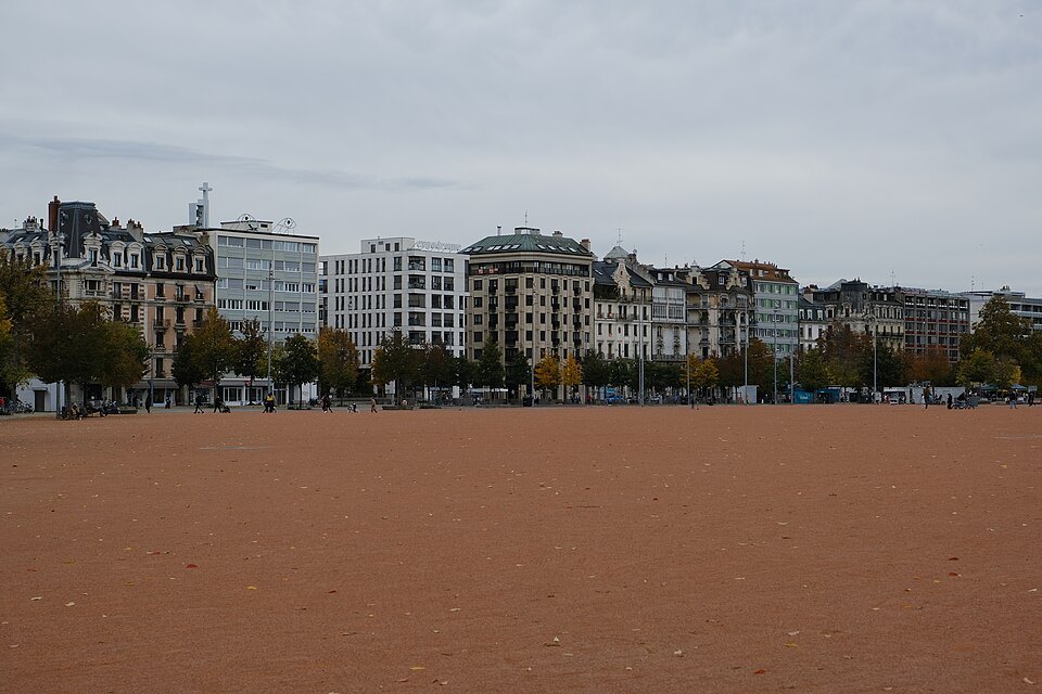 The open plain of Plainpalais under a gray sky, the city around its edges