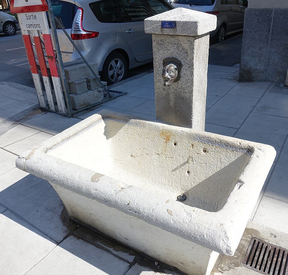 A stone drinking fountain on the pavement of the Rue des Buis