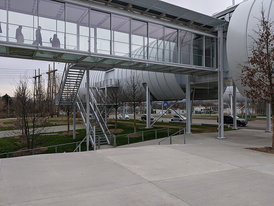 The raised glass walkway beside a CERN building on a gray day