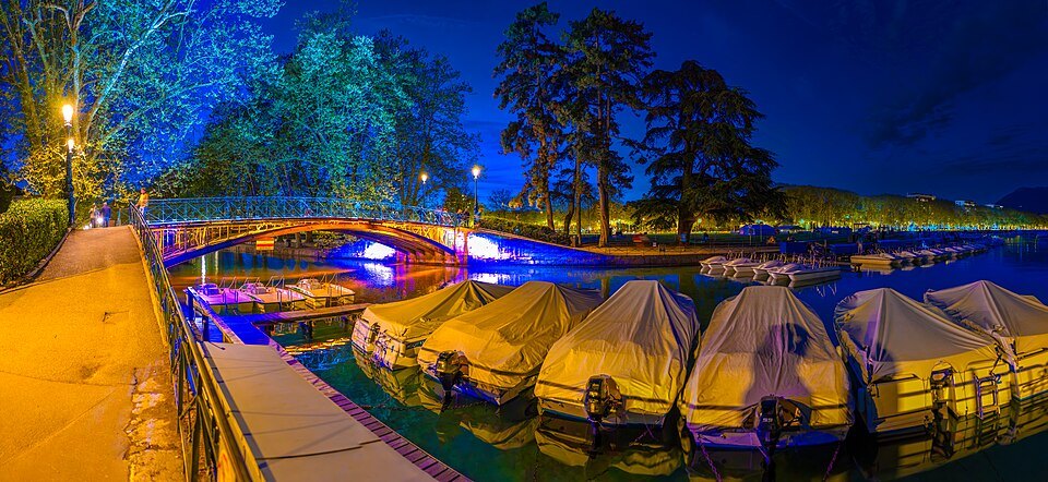 Covered boats along a lit canal in Annecy at dusk