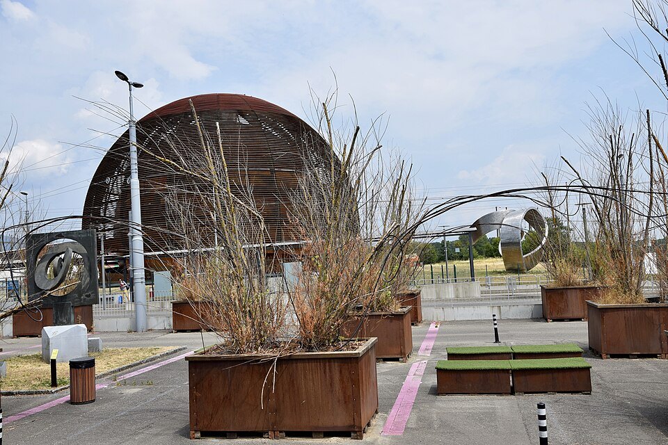 CERN's wooden Globe behind planters of tall grasses on the forecourt