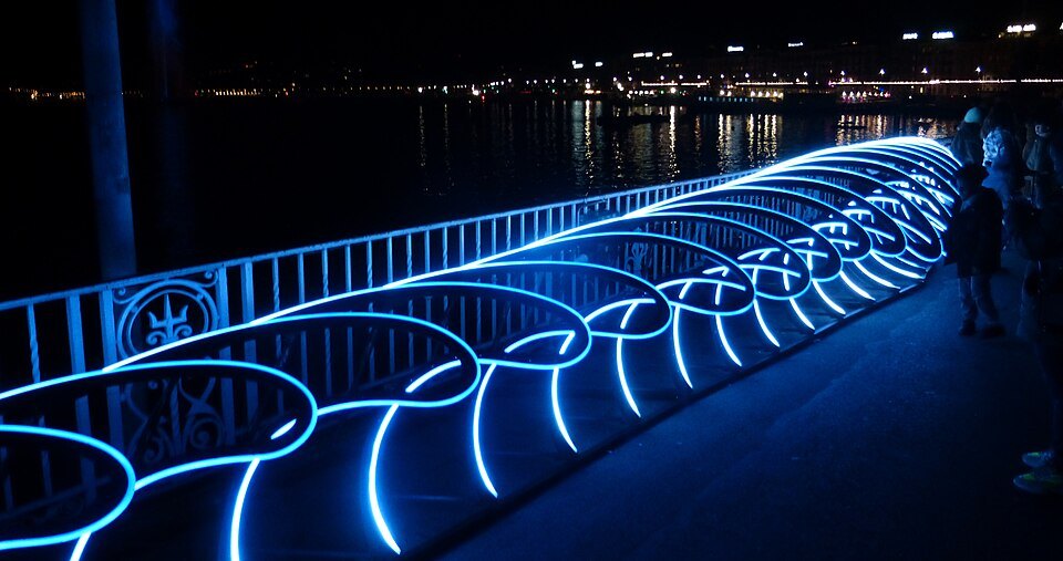 A blue light installation along a lakeside railing during Geneva Lux