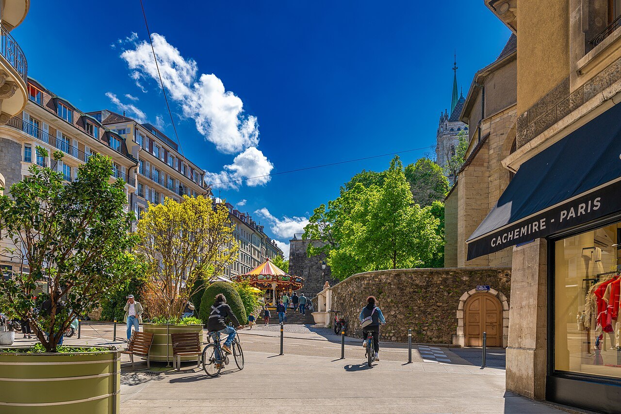 Café terraces and a carousel on an old-town street under a deep blue sky