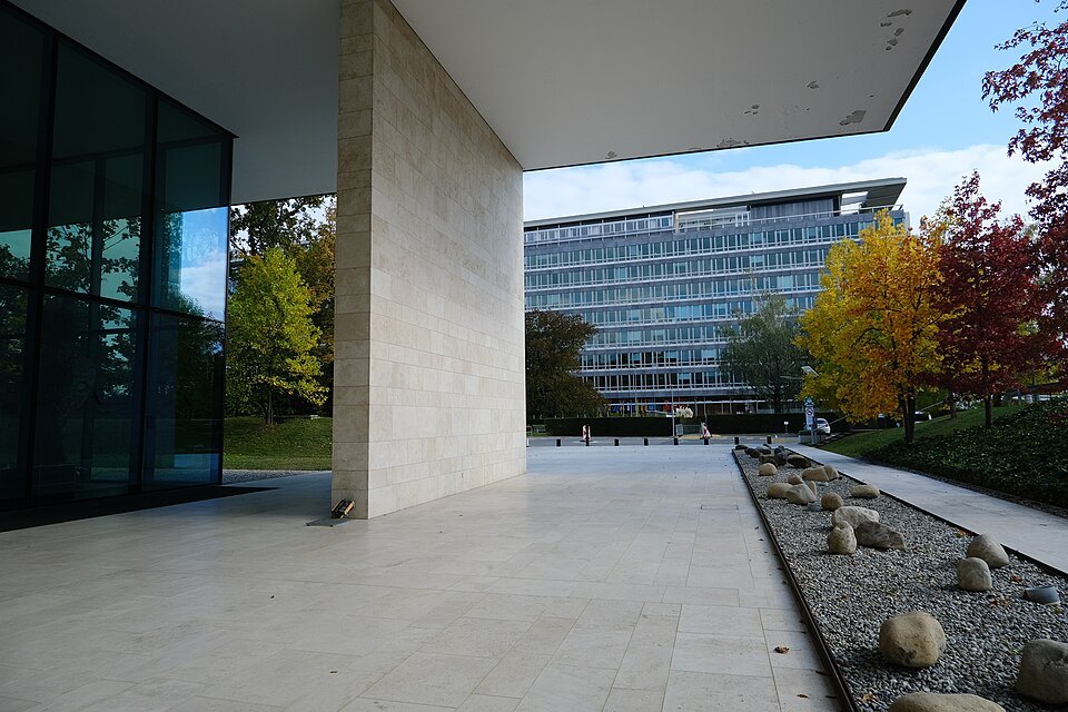 A covered walkway at the World Health Organization campus, autumn trees beyond