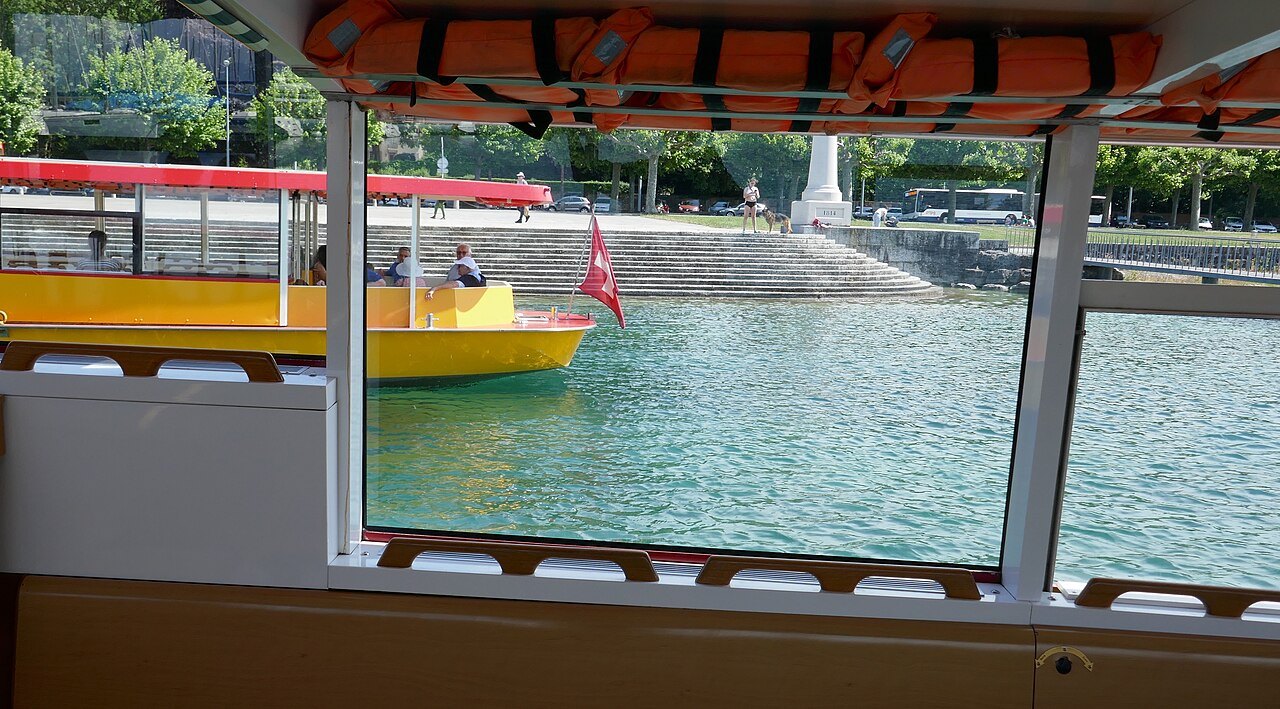 A yellow Mouette seen through the window of another crossing the harbor