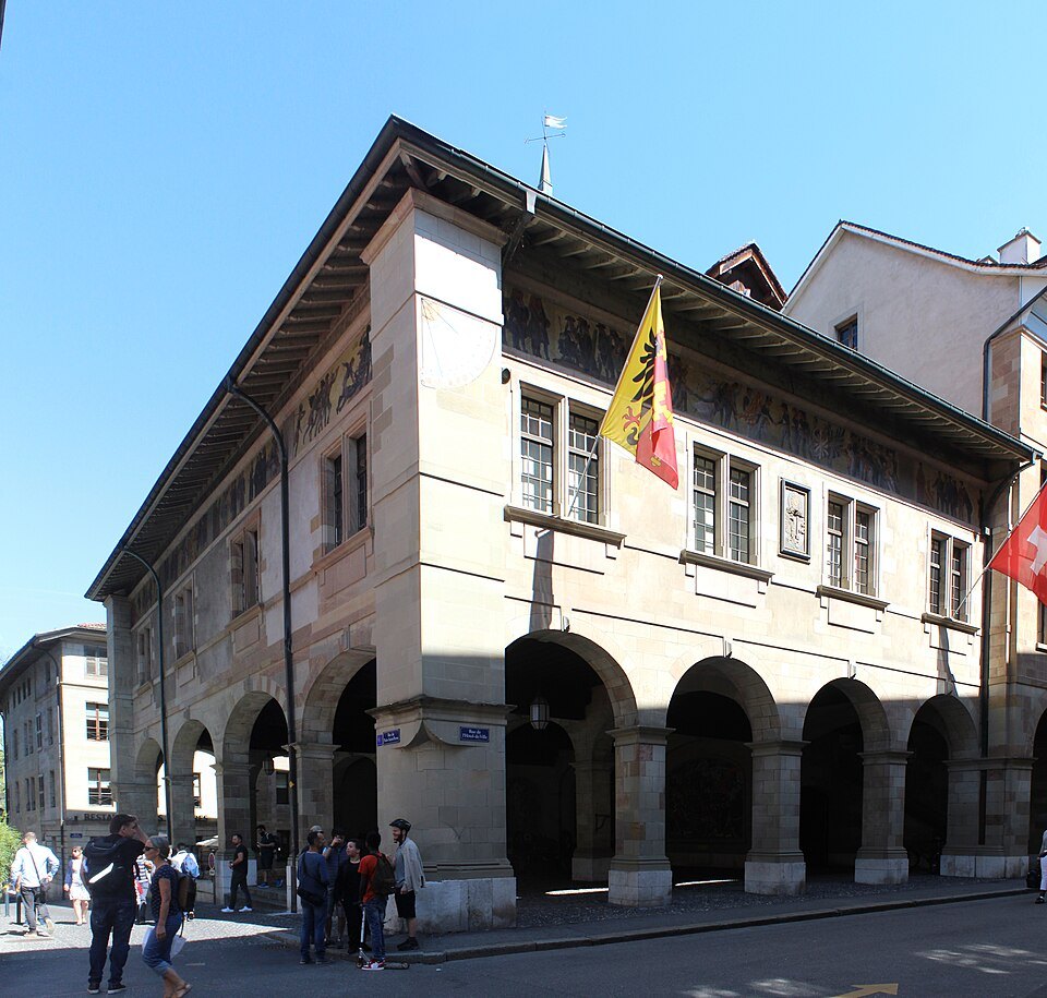 The Old Arsenal on its corner, the flag of Geneva above the arcades