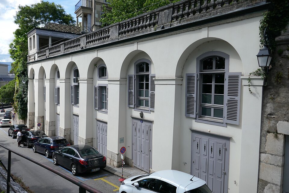 The white arched houses of the Rampe de la Treille above a row of parked cars