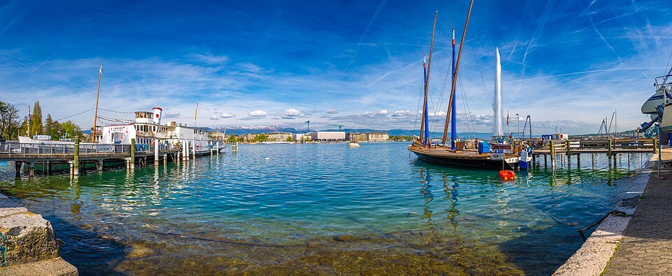 An old sailing barge moored in clear water beside the left-bank quay