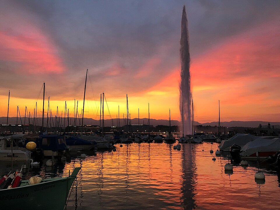 The Jet d'Eau dark against an orange sunset over the marina masts