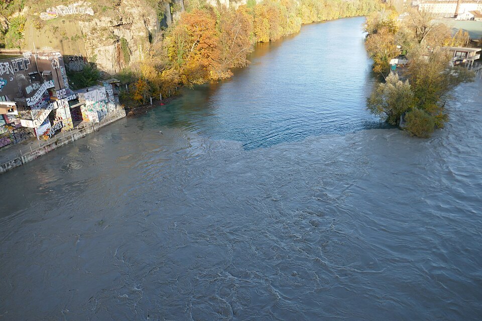The swollen Arve flowing between autumn banks below the Jonction