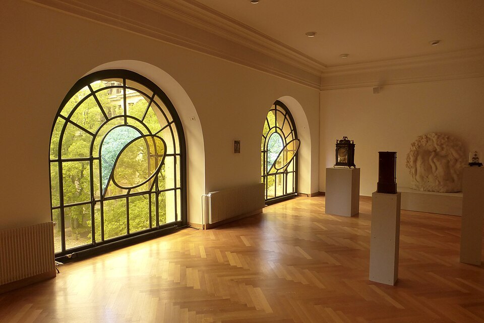 Arched stained-glass windows lighting a gallery of the Musée d'Art et d'Histoire