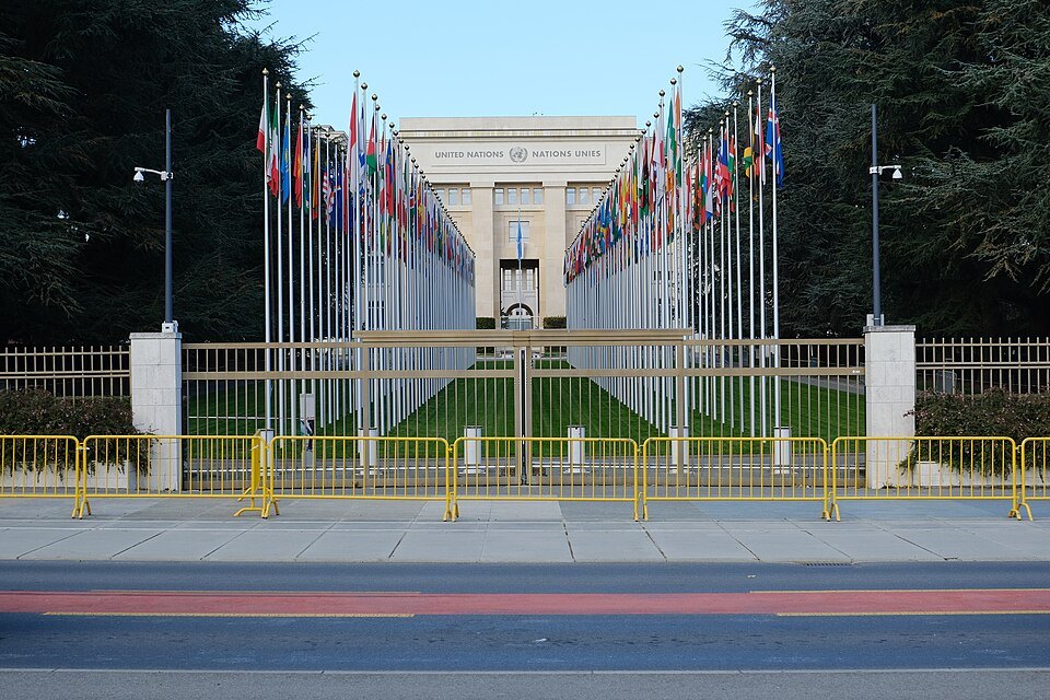 The avenue of flags leading to the Palace of Nations behind its railings