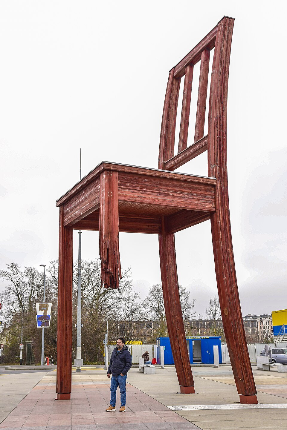 A man standing beneath the Broken Chair on the Place des Nations