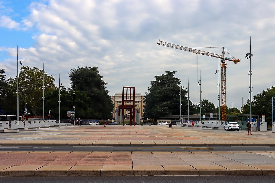 The Place des Nations and the Broken Chair under a cloudy sky, a crane at work behind