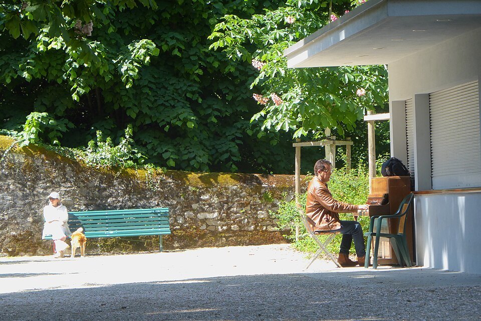 A woman at a café kiosk and a man on a bench in the Parc des Eaux-Vives