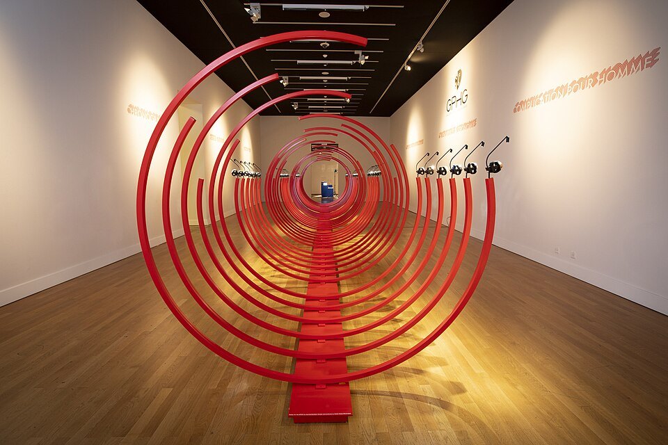 A red spiral installation filling a white exhibition gallery