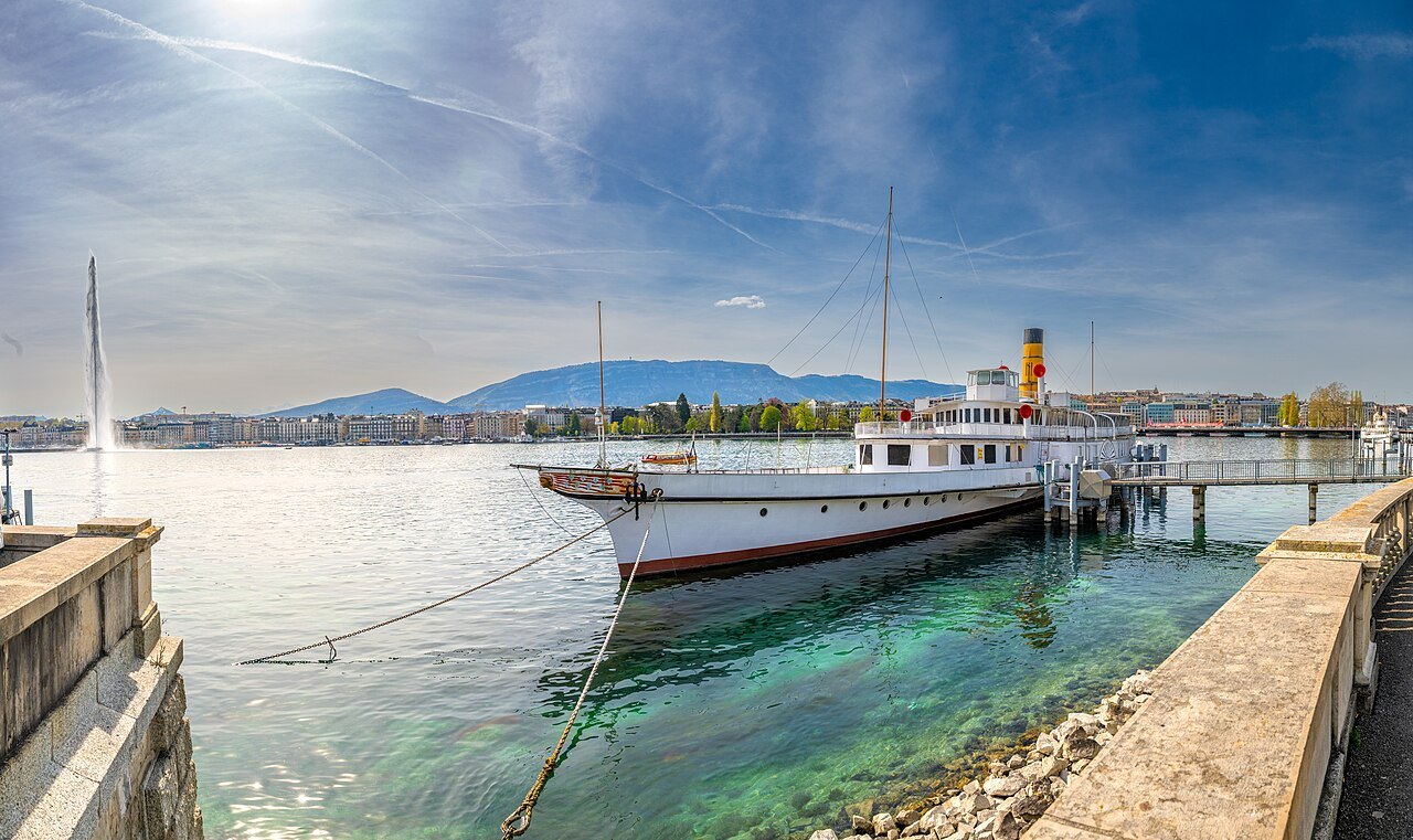 A paddle steamer moored by the quay under a clear sky, the Jet d'Eau to the left