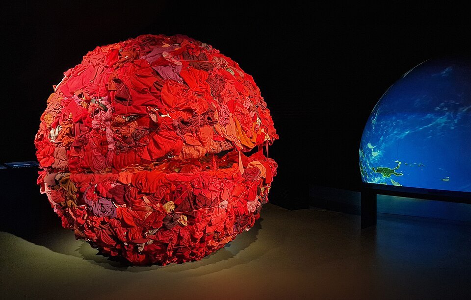 A red sculpted sphere lit in a darkened gallery of the Red Cross and Red Crescent Museum