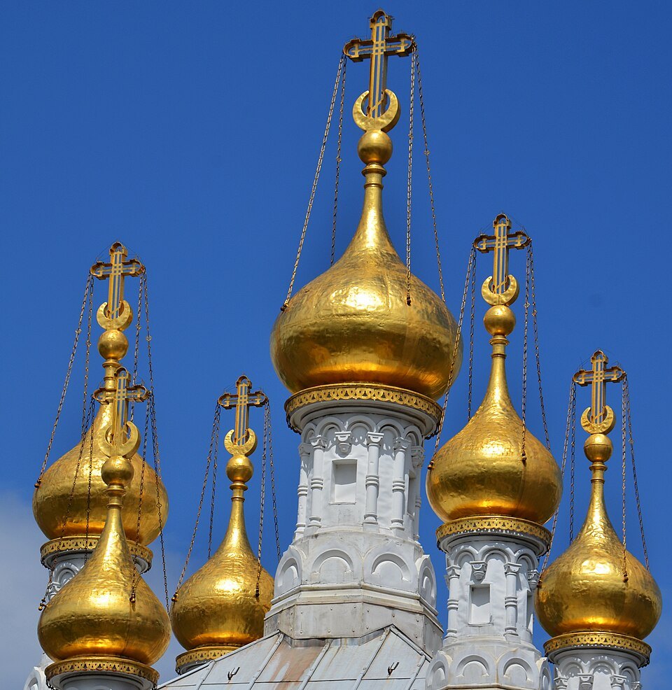 Gilded onion domes and crosses of the Russian Church against a deep blue sky